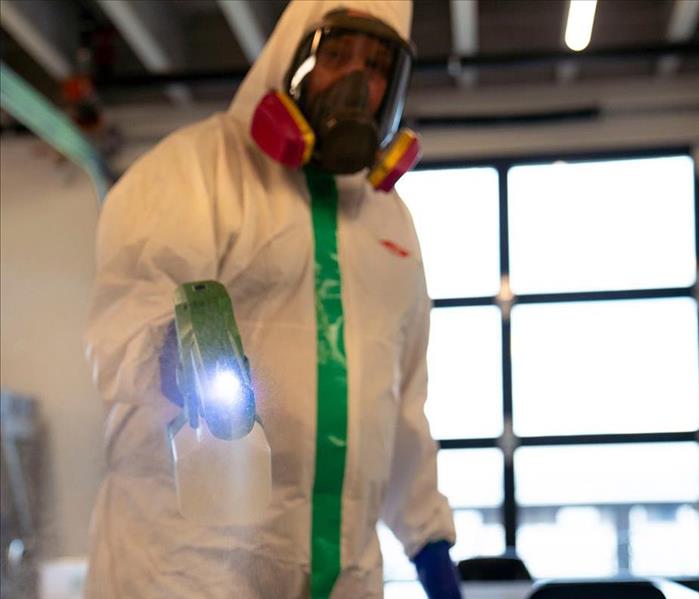 a man with an electrostatic sprayer disinfecting a table