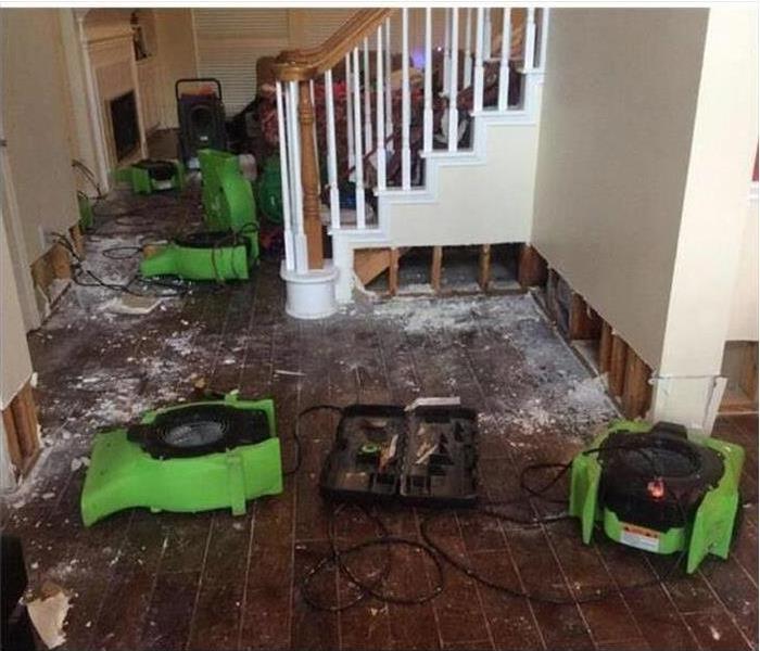 flood cuts performed in drywall, debris on floor, air movers placed on damaged area.