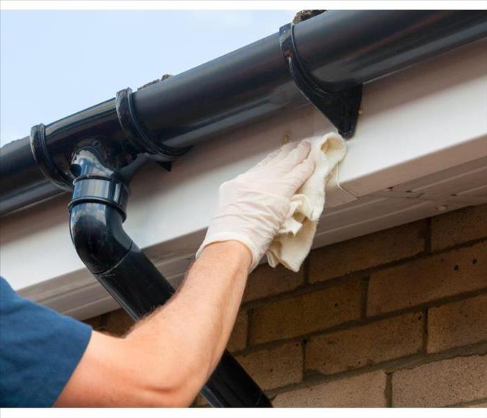 Man cleaning and maintaining plastic guttering 