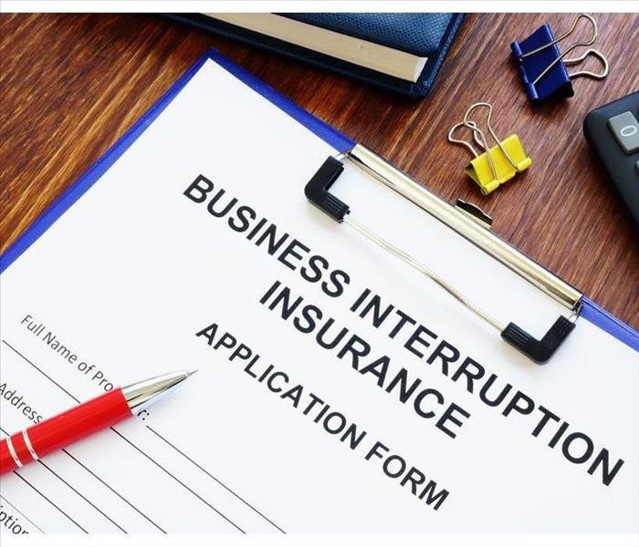 Business interruption insurance form and red pen for signing.