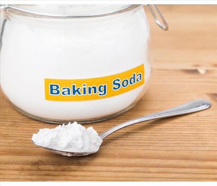Jar and spoonful of baking soda for multiple holistic usages.