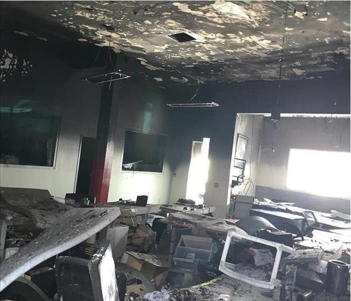 Inside of a local business, ceiling covered with black smoke, desks covered with debris, computers burnt